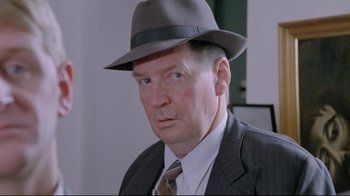 Movie still from “My Left Foot” (1989), directed by Jim Sheridan – An older man wearing a hat and a suit; Close Up shot, Over the shoulder angle