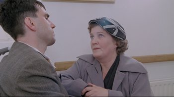 Movie still from “My Left Foot” (1989), directed by Jim Sheridan – An older woman is talking to a younger man; Close Up shot, Over the shoulder angle