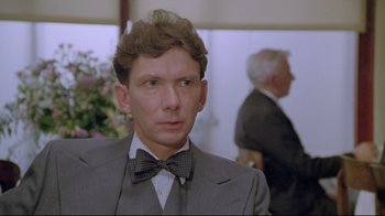 Movie still from “My Left Foot” (1989), directed by Jim Sheridan – A man wearing a suit and bow tie; Close Up shot, Over the shoulder angle