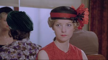 Movie still from “My Left Foot” (1989), directed by Jim Sheridan – A woman wearing a red dress and a black hat; Close Up shot, Over the shoulder angle