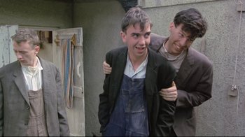 Movie still from “My Left Foot” (1989), directed by Jim Sheridan – Two men are hugging each other in front of a door; Medium shot, Low angle