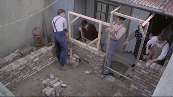 Movie still from “My Left Foot” (1989), directed by Jim Sheridan – A group of men working together on a brick wall; Wide shot, High angle