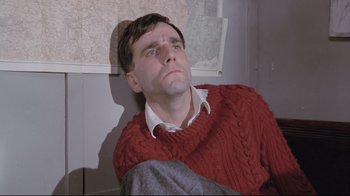 Movie still from “My Left Foot” (1989), directed by Jim Sheridan – A man in a red sweater sitting on the ground; Close Up shot, Overhead angle