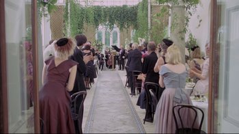 Movie still from “My Left Foot” (1989), directed by Jim Sheridan – A group of people standing in a room with chairs; Wide shot, Over the shoulder angle