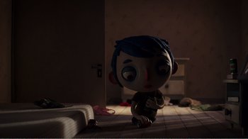 Movie still from “My Life as a Zucchini” (2016), directed by Claude Barras – A doll with blue hair sitting on the floor in a dark room; Wide shot, Overhead angle