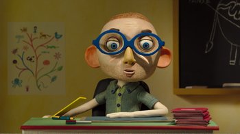Movie still from “My Life as a Zucchini” (2016), directed by Claude Barras – A clay sculpture of a man wearing glasses and sitting at a desk; Medium shot, Low angle