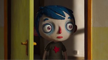 Movie still from “My Life as a Zucchini” (2016), directed by Claude Barras – A doll's face in front of a yellow door; Close Up shot, Overhead angle