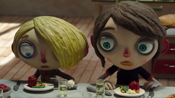 Movie still from “My Life as a Zucchini” (2016), directed by Claude Barras – A couple of people sitting at a table with plates of food on it; Close Up shot, Over the shoulder angle