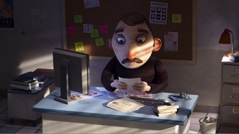 Movie still from “My Life as a Zucchini” (2016), directed by Claude Barras – A man sitting at a computer desk holding a paper; Medium shot, High angle