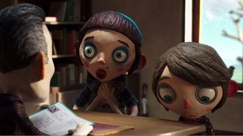 Movie still from “My Life as a Zucchini” (2016), directed by Claude Barras – A couple of people sitting at a table with a book in front of them; Medium shot, Over the shoulder angle
