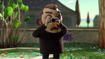 Movie still from “My Life as a Zucchini” (2016), directed by Claude Barras – A man in a brown sweater is taking a picture; Close Up shot, Low angle