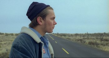 Movie still from “My Own Private Idaho” (1991), directed by Gus Van Sant – A man standing on the side of a road looking off into the distance; Close Up shot, Low angle