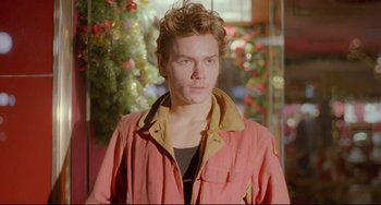 Movie still from “My Own Private Idaho” (1991), directed by Gus Van Sant – A man in a pink jacket standing in front of a christmas tree; Close Up shot, Over the shoulder angle