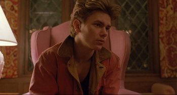 Movie still from “My Own Private Idaho” (1991), directed by Gus Van Sant – A young man sitting on a pink chair in front of a window; Close Up shot, Low angle