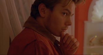 Movie still from “My Own Private Idaho” (1991), directed by Gus Van Sant – A man in a red jacket is holding his chin; Close Up shot, Over the shoulder angle