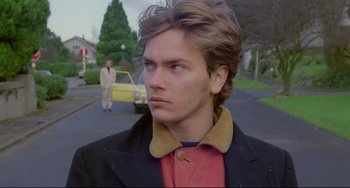 Movie still from “My Own Private Idaho” (1991), directed by Gus Van Sant – A young man standing on the side of the street; Close Up shot, Over the shoulder angle