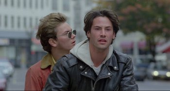 Movie still from “My Own Private Idaho” (1991), directed by Gus Van Sant – A man and a woman are standing next to each other on a street; Close Up shot, Low angle
