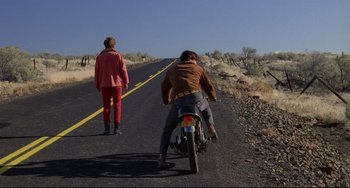 Movie still from “My Own Private Idaho” (1991), directed by Gus Van Sant – Two people riding a motorcycle down the middle of a road; Wide shot, Low angle
