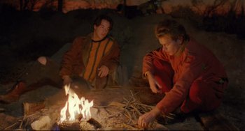 Movie still from “My Own Private Idaho” (1991), directed by Gus Van Sant – A man and a woman sitting in front of a fire; Medium shot, Low angle