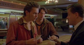 Movie still from “My Own Private Idaho” (1991), directed by Gus Van Sant – A couple of men sitting at a table with cards; Medium shot, Over the shoulder angle
