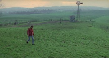 Movie still from “My Own Private Idaho” (1991), directed by Gus Van Sant – A man walking across a lush green grass covered field; Extreme Wide shot, High angle