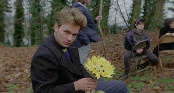 Movie still from “My Own Private Idaho” (1991), directed by Gus Van Sant – A young man holding a yellow flower in a forest; Close Up shot, Over the shoulder angle