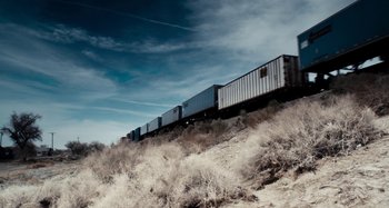 Movie still from “My Son, My Son, What Have Ye Done” (2009), directed by Werner Herzog – A train traveling down train tracks through a field; Extreme Wide shot, Low angle