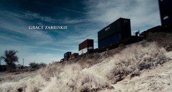 Movie still from “My Son, My Son, What Have Ye Done” (2009), directed by Werner Herzog – A train traveling down train tracks next to a field; Extreme Wide shot, Overhead angle