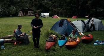 Movie still from “My Son, My Son, What Have Ye Done” (2009), directed by Werner Herzog – A man standing next to a group of kayaks; Wide shot, High angle