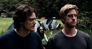 Movie still from “My Son, My Son, What Have Ye Done” (2009), directed by Werner Herzog – Two men standing next to each other in a field; Medium shot, Over the shoulder angle