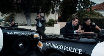 Movie still from “My Son, My Son, What Have Ye Done” (2009), directed by Werner Herzog – Two men in suits are sitting in a police car; Wide shot, High angle