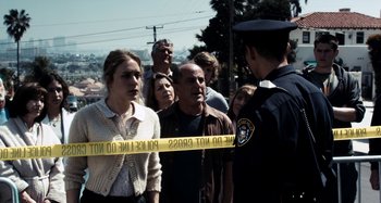 Movie still from “My Son, My Son, What Have Ye Done” (2009), directed by Werner Herzog – A group of people standing next to a police officer; Medium shot, Over the shoulder angle