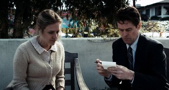 Movie still from “My Son, My Son, What Have Ye Done” (2009), directed by Werner Herzog – A man and a woman sitting on a bench looking at a paper; Medium shot, Over the shoulder angle