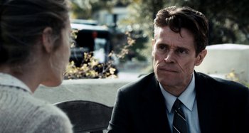 Movie still from “My Son, My Son, What Have Ye Done” (2009), directed by Werner Herzog – A man wearing a suit and tie sitting next to a woman; Close Up shot, Over the shoulder angle