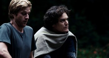 Movie still from “My Son, My Son, What Have Ye Done” (2009), directed by Werner Herzog – A man wrapped in a blanket looks at the camera; Medium shot, Low angle