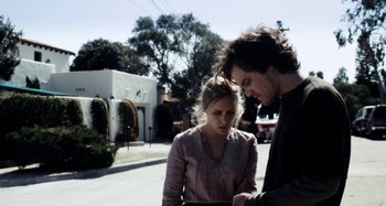 Movie still from “My Son, My Son, What Have Ye Done” (2009), directed by Werner Herzog – A man and a woman standing on the side of a road; Medium shot, Low angle