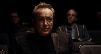 Movie still from “My Son, My Son, What Have Ye Done” (2009), directed by Werner Herzog – A man in a suit sitting next to another man in a suit; Close Up shot, Over the shoulder angle