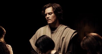 Movie still from “My Son, My Son, What Have Ye Done” (2009), directed by Werner Herzog – A man in a robe and a woman in a black dress; Medium shot, Low angle