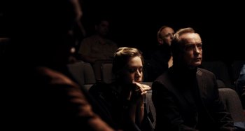 Movie still from “My Son, My Son, What Have Ye Done” (2009), directed by Werner Herzog – A group of people sitting in a dark room; Medium shot, Over the shoulder angle