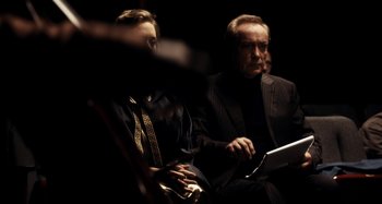 Movie still from “My Son, My Son, What Have Ye Done” (2009), directed by Werner Herzog – A man in a suit and tie sitting next to another man in a suit and tie; Medium shot, Over the shoulder angle