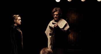 Movie still from “My Son, My Son, What Have Ye Done” (2009), directed by Werner Herzog – A man holding a microphone in a dark room; Medium shot, Over the shoulder angle