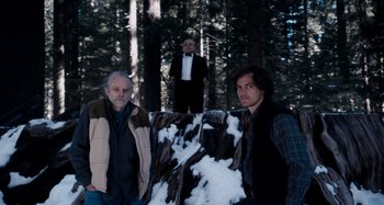 Movie still from “My Son, My Son, What Have Ye Done” (2009), directed by Werner Herzog – A group of men standing next to each other in the woods; Wide shot, Over the shoulder angle