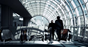 Movie still from “My Son, My Son, What Have Ye Done” (2009), directed by Werner Herzog – Two people are walking through an airport tunnel; Wide shot, Low angle
