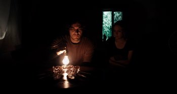 Movie still from “My Son, My Son, What Have Ye Done” (2009), directed by Werner Herzog – A man and a woman sitting in front of a lit candle; Medium shot, Low angle