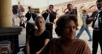 Movie still from “My Son, My Son, What Have Ye Done” (2009), directed by Werner Herzog – A group of people playing music on a street; Medium shot, Over the shoulder angle