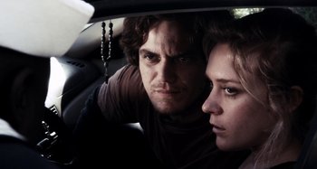Movie still from “My Son, My Son, What Have Ye Done” (2009), directed by Werner Herzog – A man and a woman sitting in the back seat of a car; Close Up shot, Low angle