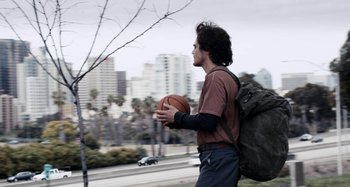 Movie still from “My Son, My Son, What Have Ye Done” (2009), directed by Werner Herzog – A man holding a basketball in his hands; Wide shot, Low angle
