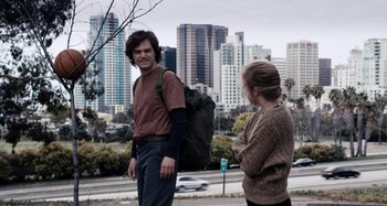 Movie still from “My Son, My Son, What Have Ye Done” (2009), directed by Werner Herzog – A man and a woman standing next to each other on the side of a road; Medium shot, Over the shoulder angle