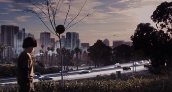 Movie still from “My Son, My Son, What Have Ye Done” (2009), directed by Werner Herzog – Cars driving down a street near a tree; Extreme Wide shot, High angle