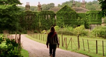 Movie still from “My Summer of Love” (2004), directed by Pawel Pawlikowski – A woman walking down a path in front of a house; Wide shot, Low angle